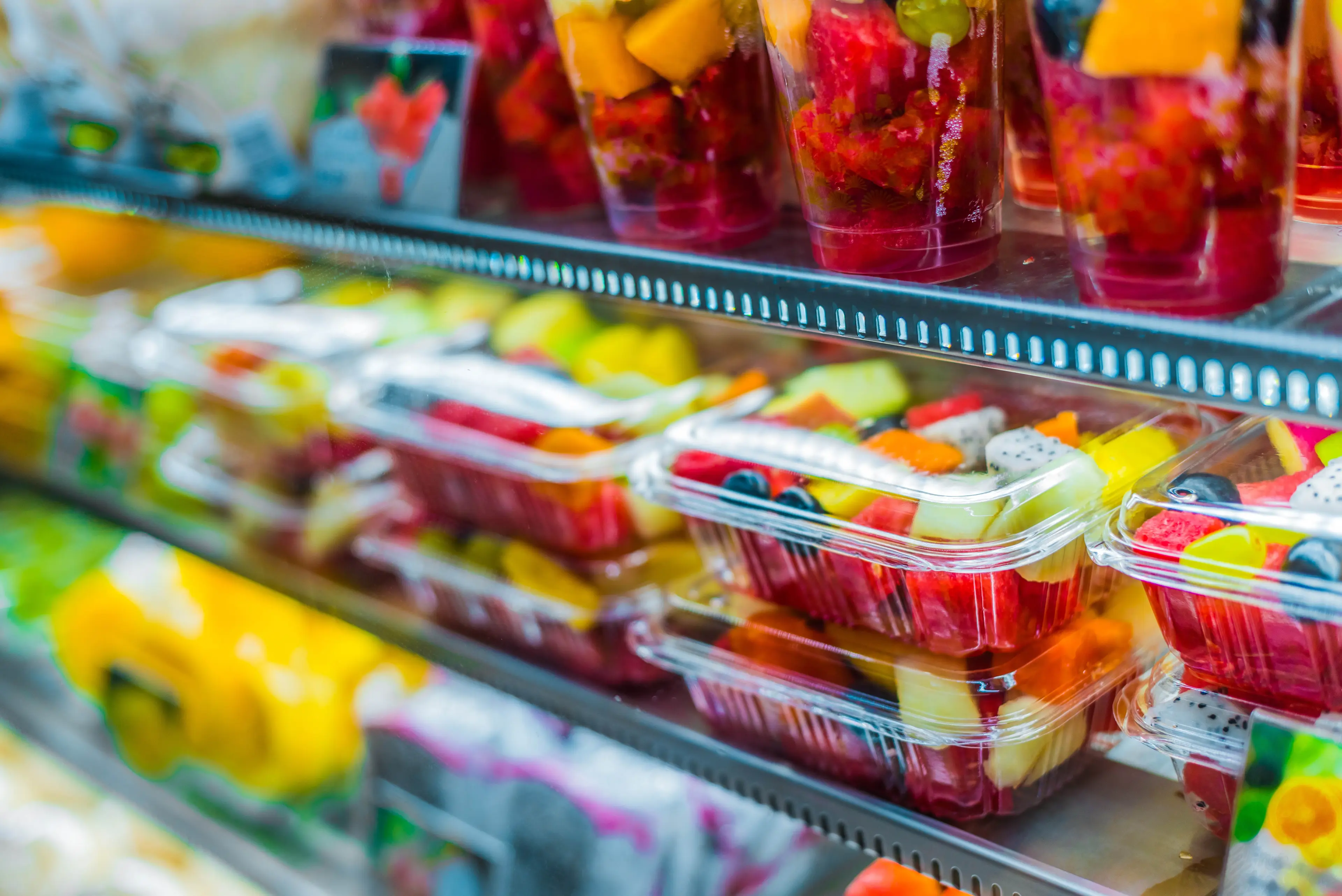 Supermarket shelf displaying fresh fruit in rigid plastic containers