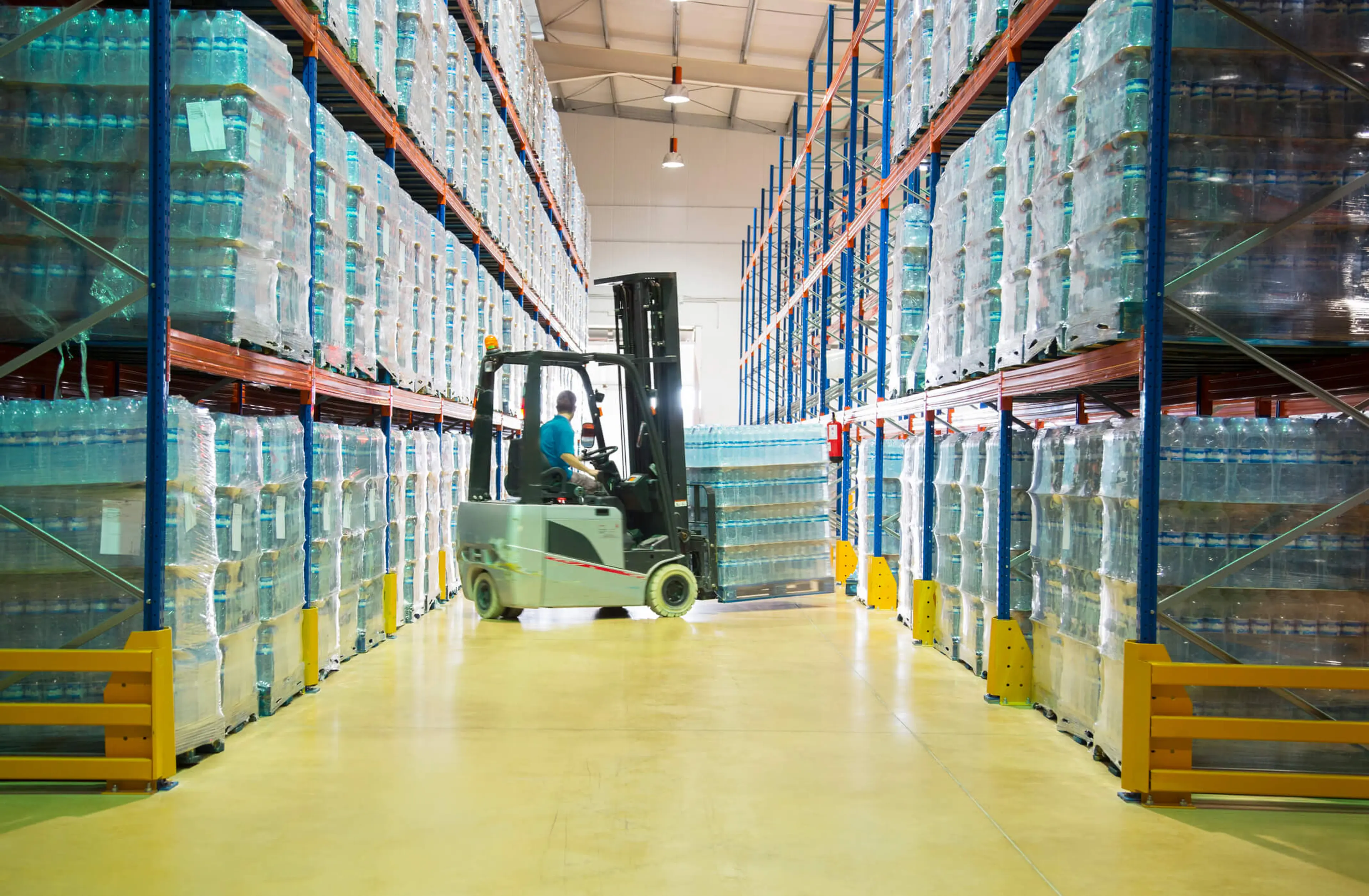 A warehouse scene with a forklift in action, transporting goods on its sturdy forks amidst stacks of stretch film.